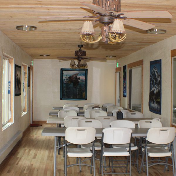 Breakout room off the Dining Hall with tables, chairs, ceiling fans, and quilted wall hangings.